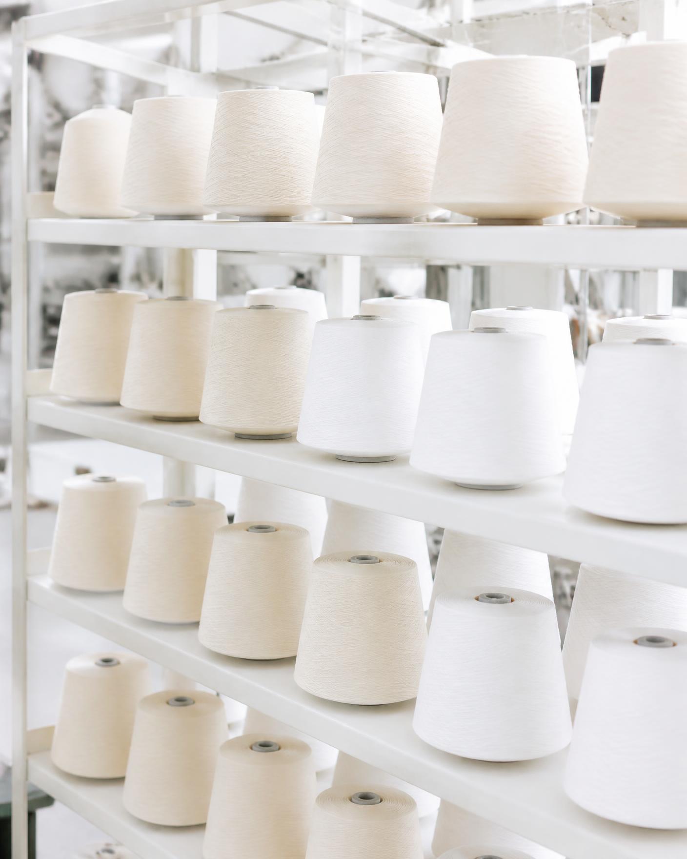 Racks of cream and white yarn cones in the winding hall